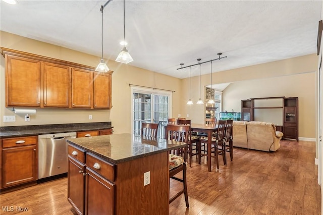 kitchen featuring decorative light fixtures, a center island, stainless steel dishwasher, wood-type flooring, and a breakfast bar area