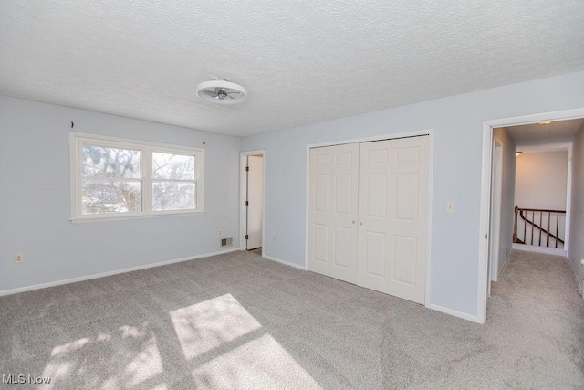 unfurnished bedroom with a textured ceiling, a closet, and light carpet