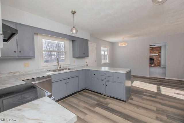 kitchen featuring gray cabinetry, kitchen peninsula, hanging light fixtures, and sink