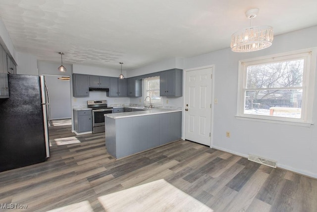 kitchen featuring hanging light fixtures, kitchen peninsula, appliances with stainless steel finishes, and sink