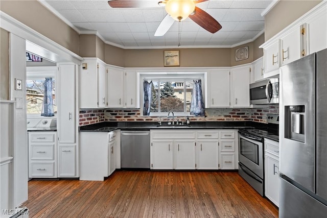 kitchen featuring a sink, stainless steel appliances, dark countertops, and white cabinets