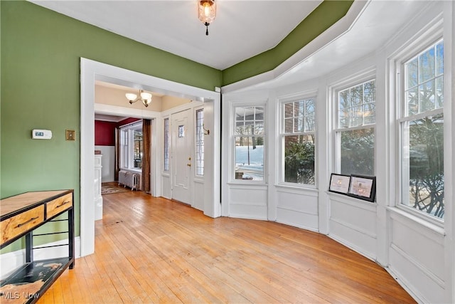 foyer featuring a healthy amount of sunlight, light wood-type flooring, radiator heating unit, and an inviting chandelier