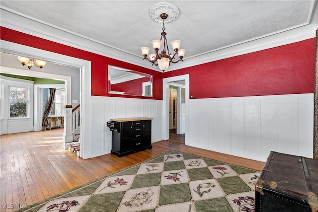 dining space with stairway, an inviting chandelier, wainscoting, and hardwood / wood-style flooring