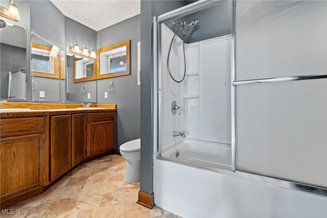 full bathroom with enclosed tub / shower combo, double vanity, toilet, and a sink