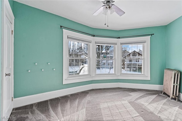 unfurnished room featuring carpet flooring, baseboards, a ceiling fan, and radiator heating unit