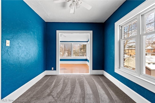 spare room with a textured wall, ceiling fan, baseboards, and carpet floors