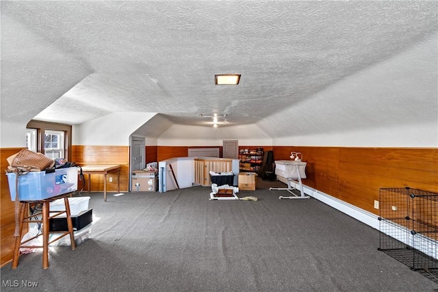 bonus room with a wainscoted wall, wood walls, lofted ceiling, carpet floors, and a textured ceiling