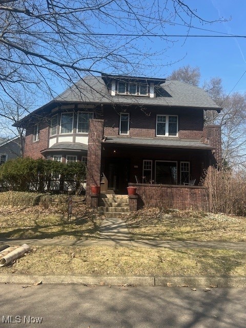 american foursquare style home featuring brick siding and covered porch