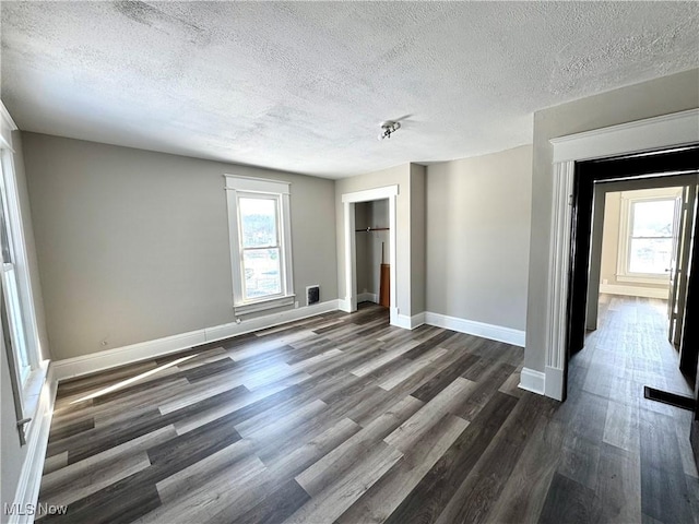 unfurnished room featuring dark wood-type flooring and a textured ceiling