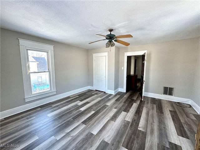 empty room featuring a textured ceiling and dark hardwood / wood-style floors