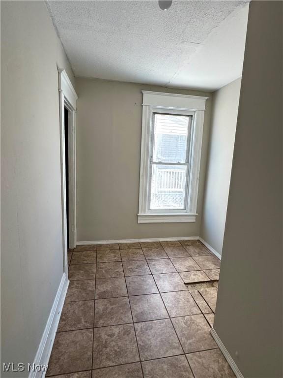 unfurnished room featuring a textured ceiling and tile patterned flooring