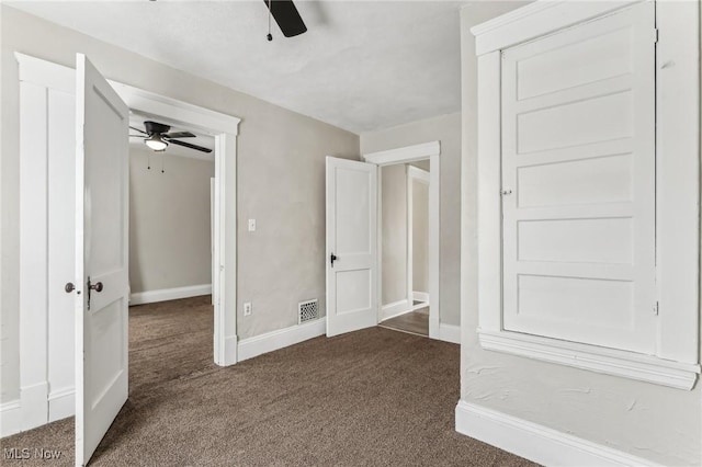 unfurnished bedroom with ceiling fan and dark carpet