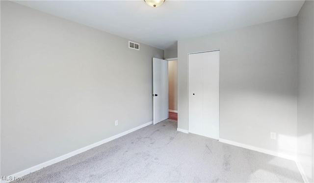 unfurnished bedroom with light colored carpet and a closet