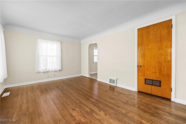 spare room with dark hardwood / wood-style floors and a textured ceiling