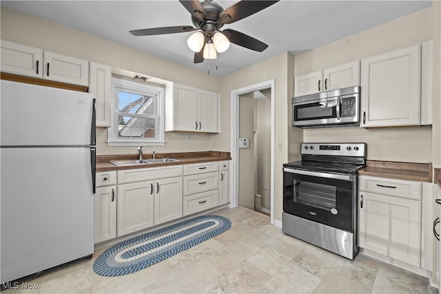 kitchen with ceiling fan, appliances with stainless steel finishes, white cabinetry, and sink