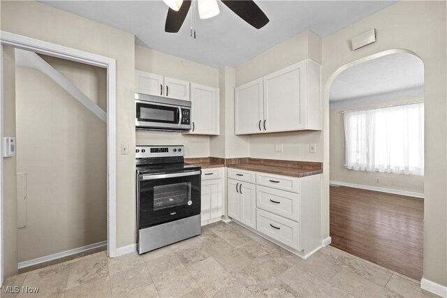 kitchen with wood counters, appliances with stainless steel finishes, white cabinets, and ceiling fan