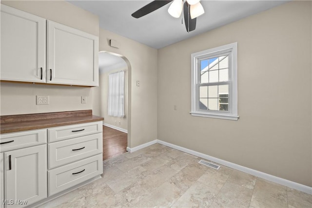 kitchen featuring ceiling fan, white cabinets, and wooden counters