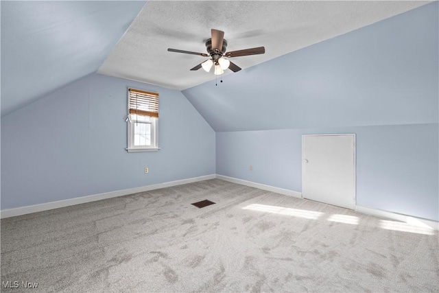 bonus room featuring ceiling fan, vaulted ceiling, carpet floors, and a textured ceiling