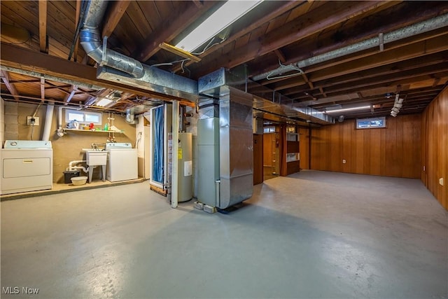 basement with water heater, heating unit, independent washer and dryer, and wood walls