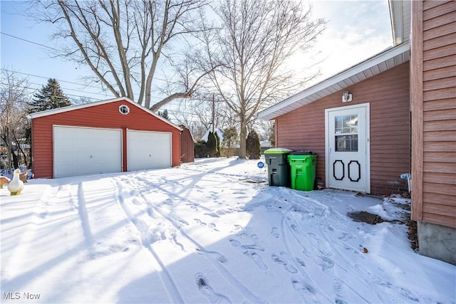 yard layered in snow with an outbuilding and a garage