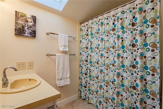 bathroom with a textured ceiling, vanity, and a skylight