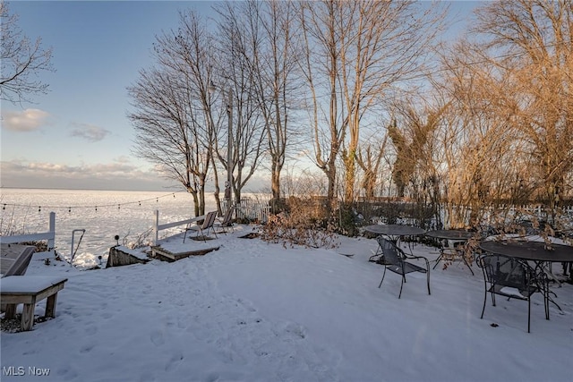 yard layered in snow featuring a water view