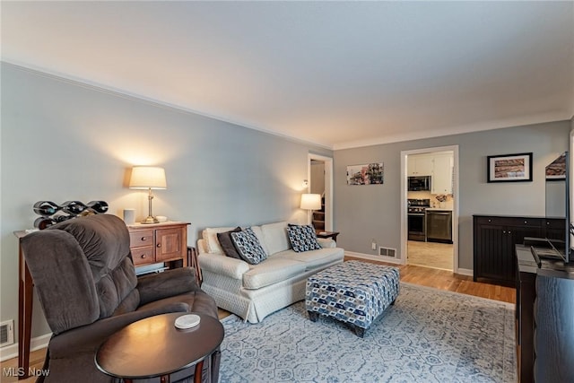 living room featuring crown molding and light wood-type flooring