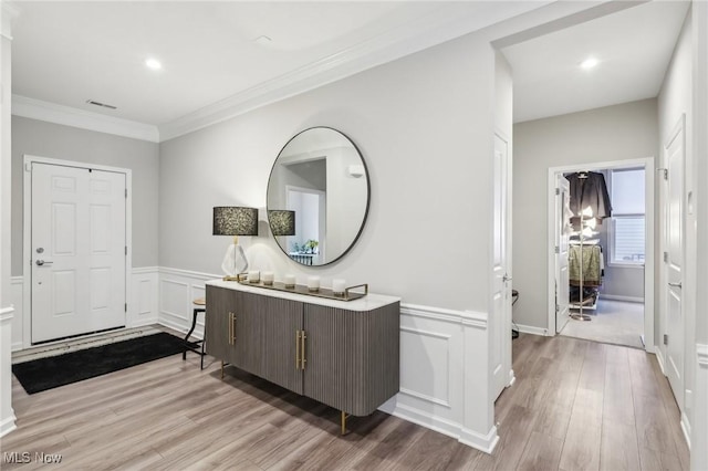 entrance foyer featuring crown molding and light hardwood / wood-style floors