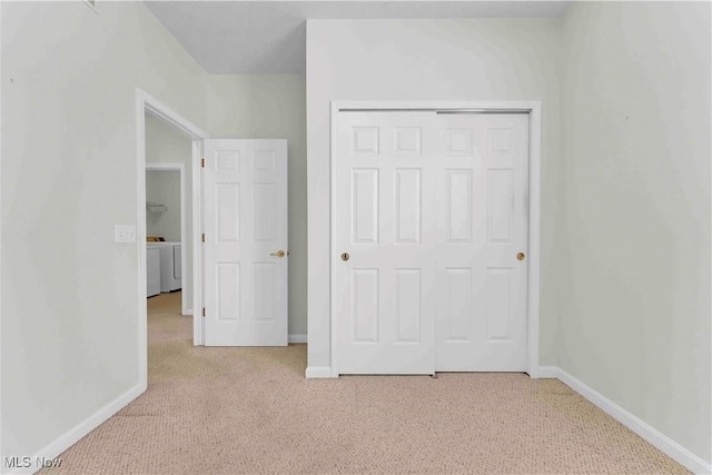 unfurnished bedroom with light carpet, a closet, and washer / dryer