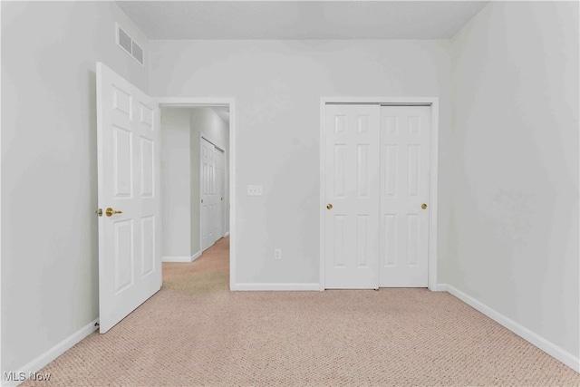 unfurnished bedroom with light carpet and a closet