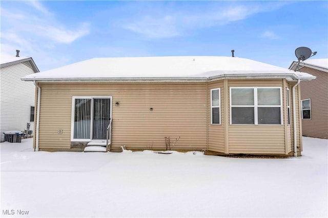 snow covered back of property featuring central air condition unit