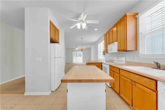 kitchen featuring butcher block counters, a center island, white appliances, ceiling fan with notable chandelier, and sink