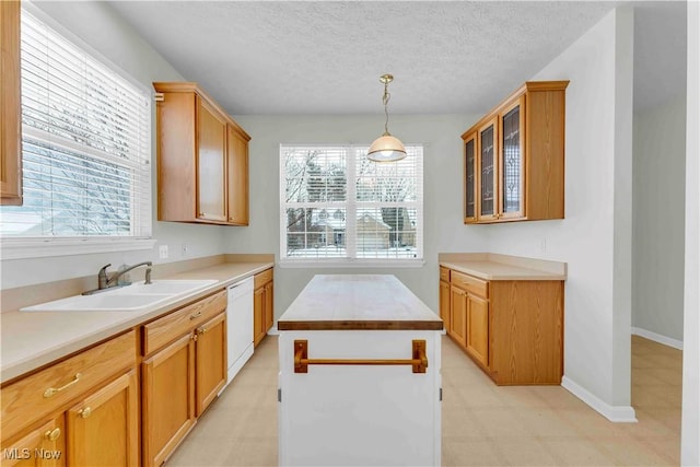 kitchen with dishwasher, a textured ceiling, a kitchen island, pendant lighting, and sink