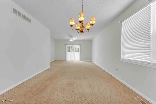 spare room featuring a textured ceiling, ceiling fan with notable chandelier, and light colored carpet