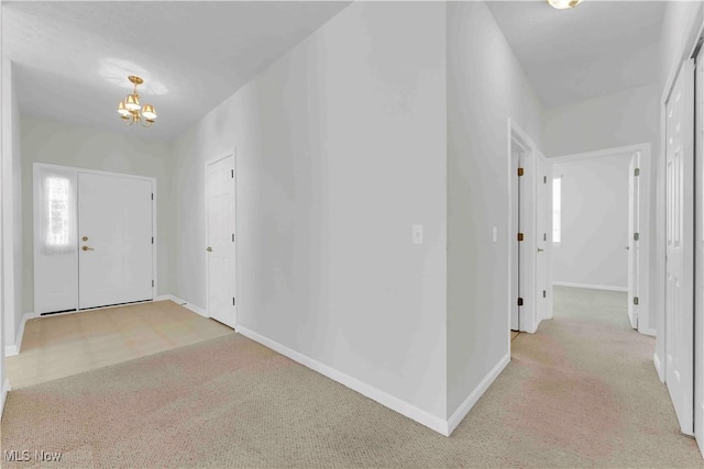 entrance foyer with an inviting chandelier and light colored carpet