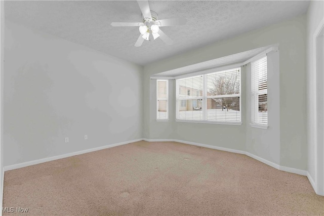 unfurnished room with ceiling fan, a textured ceiling, and light carpet