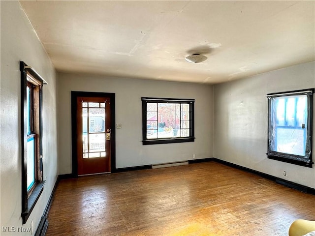 spare room featuring baseboard heating and wood-type flooring