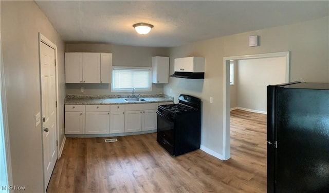 kitchen with range hood, black appliances, sink, white cabinetry, and light hardwood / wood-style flooring