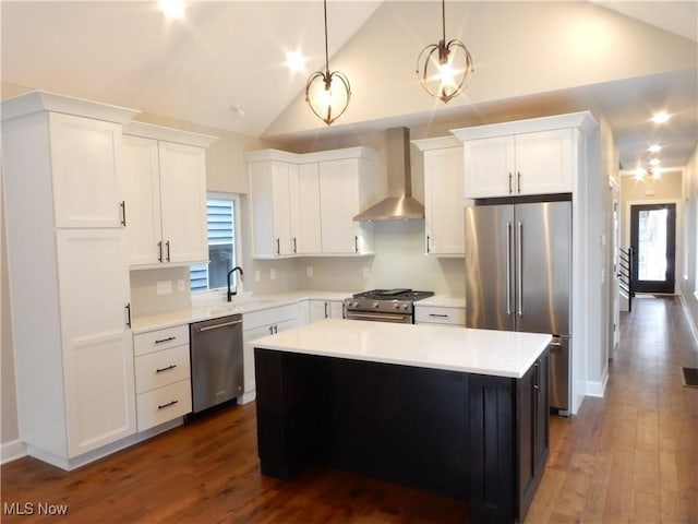 kitchen with hanging light fixtures, wall chimney exhaust hood, high quality appliances, and a kitchen island