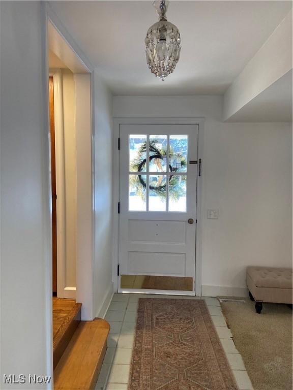 doorway with tile patterned flooring and a notable chandelier