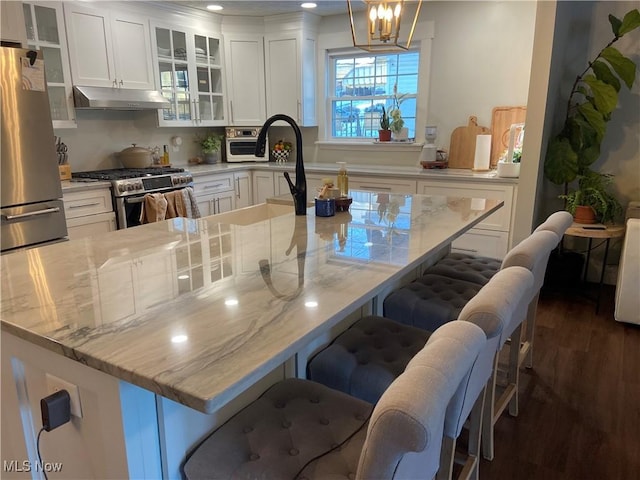 kitchen with stainless steel appliances, pendant lighting, a breakfast bar, and light stone countertops