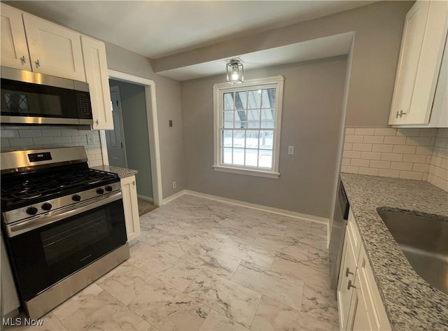 kitchen featuring light stone countertops, white cabinetry, appliances with stainless steel finishes, and tasteful backsplash