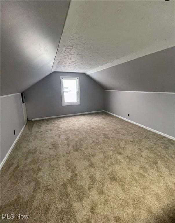 bonus room with vaulted ceiling, carpet, and a textured ceiling