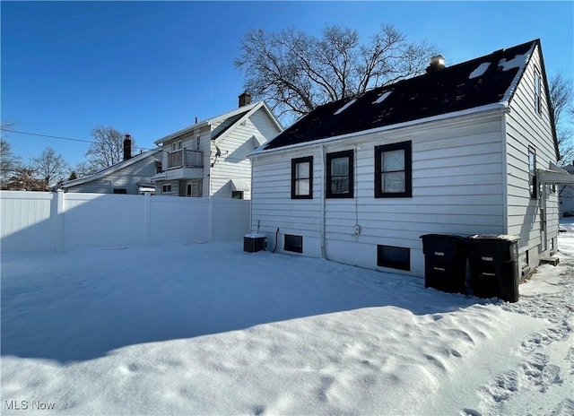 snow covered rear of property featuring central AC