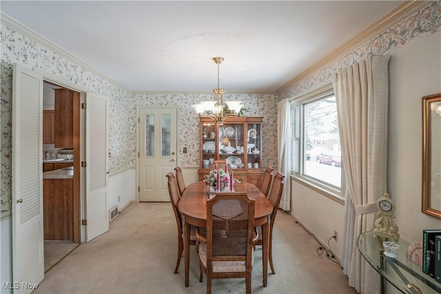 carpeted dining space with an inviting chandelier and ornamental molding