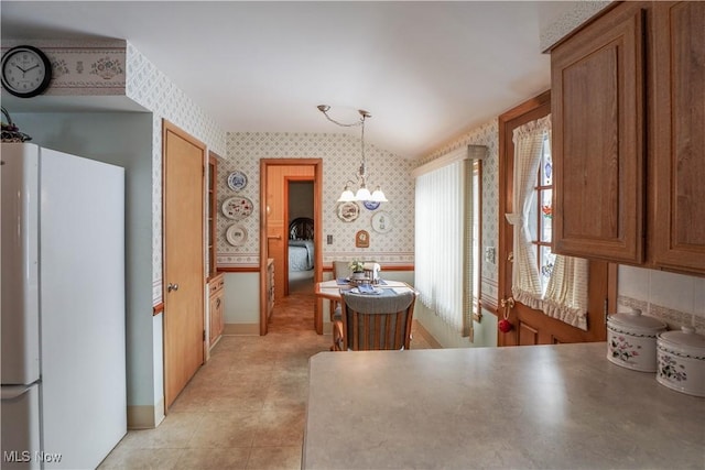 kitchen with an inviting chandelier, white refrigerator, and pendant lighting