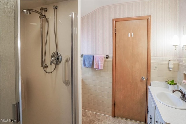 bathroom with walk in shower, vanity, tile walls, and tile patterned floors