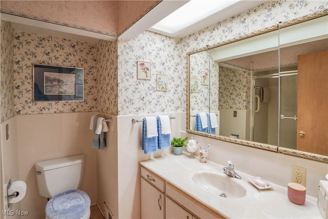 bathroom with toilet, vanity, and a shower with door