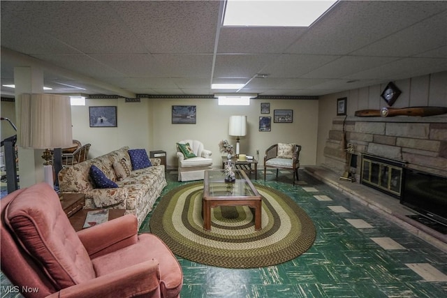 living room featuring a paneled ceiling and a stone fireplace