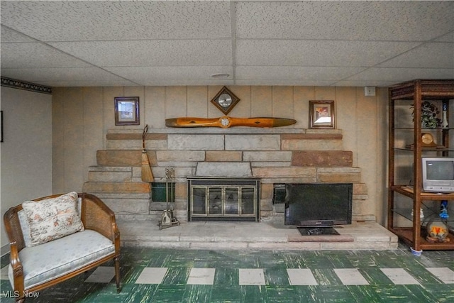 unfurnished room with a paneled ceiling and a stone fireplace